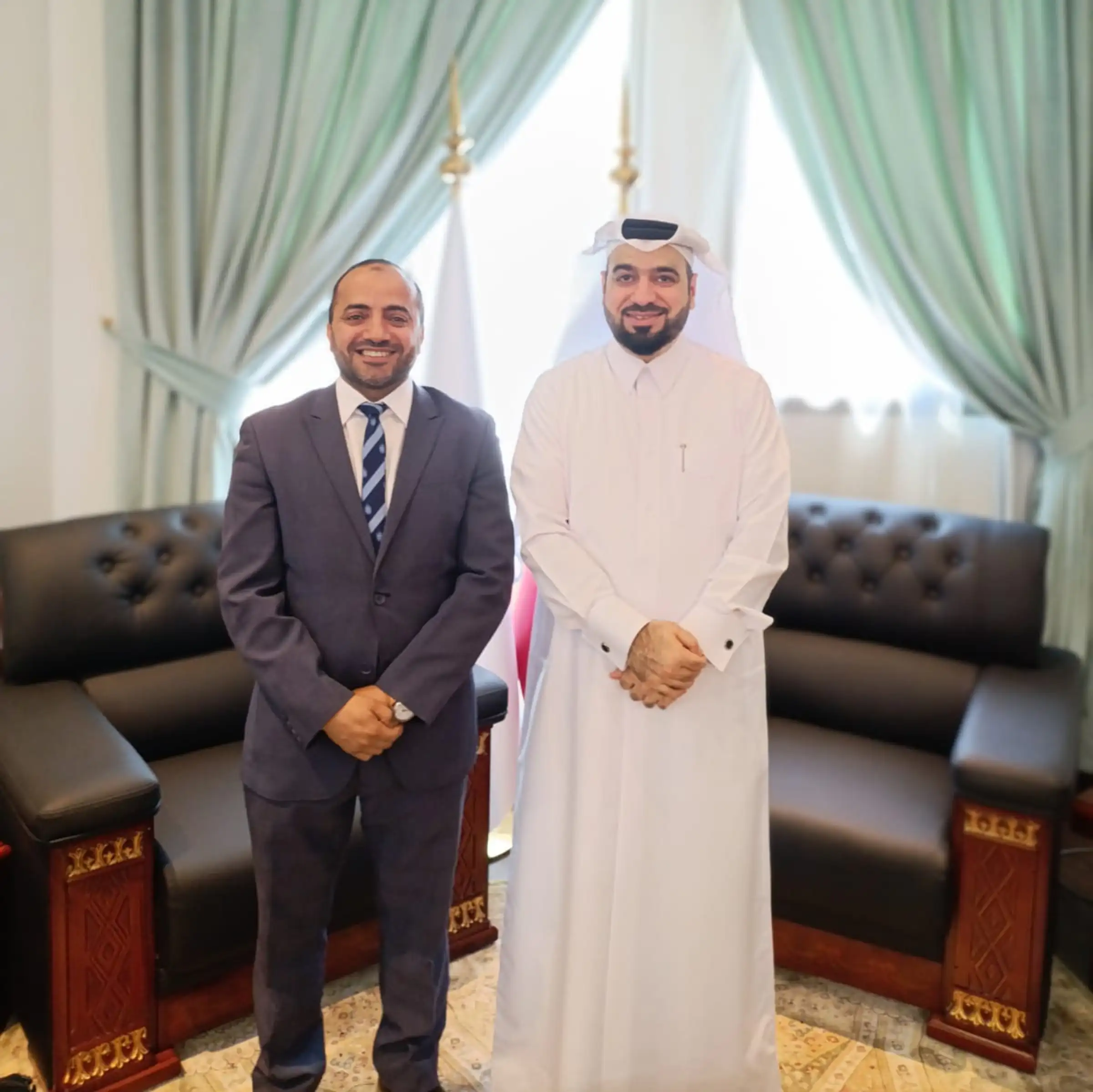 Two partners standing together in a formal reception room, ahead of a meeting